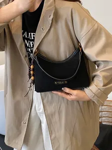 Minimalist black suede dumpling crossbody bag with wooden bead charm and metal plate