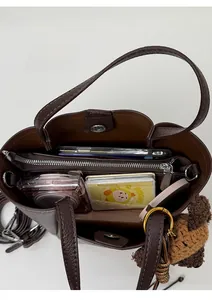 Vue intérieure du sac seau en cuir marron montrant compartiments et accessoires
