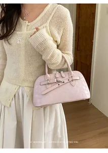 Detail of pink retro shell handbag featuring textured leather and silver buckles