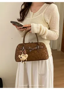 Detail of vintage brown textured leather shell bag with plush teddy bear charm