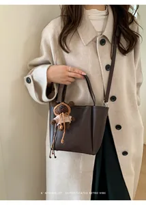 Détail du sac seau rétro en cuir marron à grain de litchi avec pendentif ours mignon