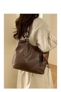Close-up of a large dark brown leather tote bag with a checkered shell charm and tassel
