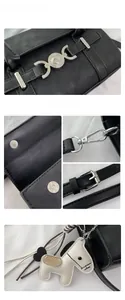 Détails du sac baguette en similicuir noir avec fermoir magnétique et pendentif cheval