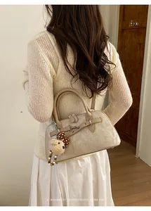 Detail view of beige retro shell bag with leather texture and cute plush bear charm