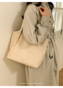 Detailed macro view of the beige leather tote bag with adjustable strap and metal hardware