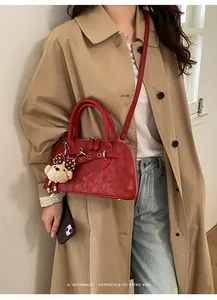 Detail view of retro red shell bag with glossy leather texture and cute bear charm