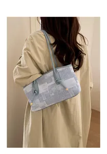 Détail du sac cabas bleu et blanc avec bandoulière en cuir nouée et logo doré chic