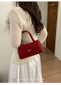 Detail view of a red cylindrical bowling bag with silver chain strap on a model