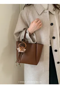 Sac seau en cuir marron avec breloque ours présenté dans un cadre de style de vie chic