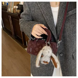 Detail of dark wine red embossed barrel bag with cute bunny pendant and shoulder strap