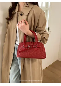 Close-up of red vintage textured leather handbag styled with a khaki trench coat and jeans