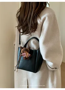 Détail du sac seau en cuir noir texturé avec un joli petit ours brun en peluche attaché