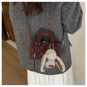 Detail of dark red Boston bag with floral embossing and cute rabbit plush charm
