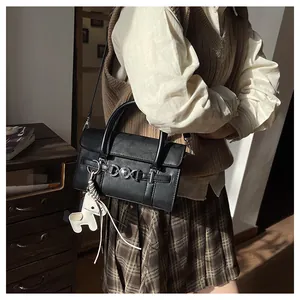 Détail d'un sac baguette en cuir noir avec boucle en métal et breloque poney blanc