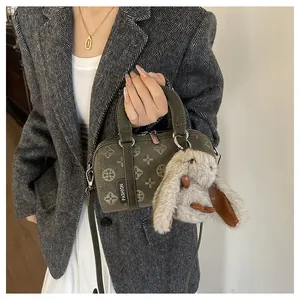 Detail of olive green baguette bag with embossed clover pattern and cute bunny charm