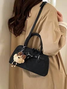 Frosted black shell handbag with bear charm and adjustable strap shown on model