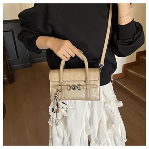 Détail du sac baguette beige avec boucle coeur, breloque cheval et ruban rayé