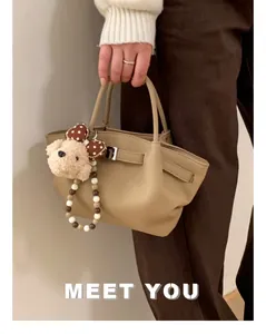 Detail of khaki leather bucket bag with silver buckle and plush dog charm accessory