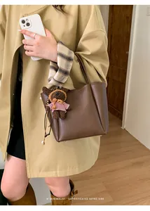 Vue détaillée du sac seau en cuir marron avec un charmant pendentif d'ours rayé