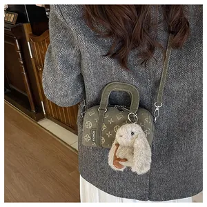 Close-up of olive green mini Boston bag with vintage prints and plush rabbit charm
