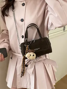 Deep brown suede mini Boston bag with chain strap and teddy bear charm on model