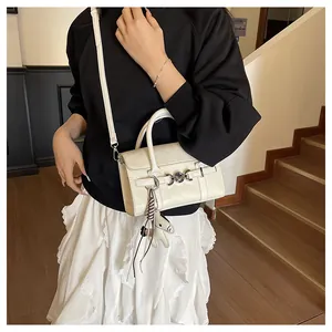 Détail d'un sac baguette en cuir PU blanc crème avec charm cheval et accessoire tissé main