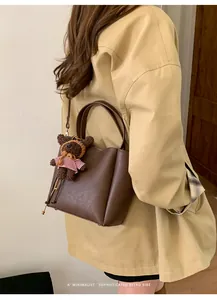 Détail du sac seau en cuir marron foncé avec un charmant pendentif en forme d'ours brun
