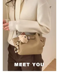 Detail of light brown lychee grain leather bucket bag with cute bear charm and bead strap