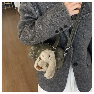 Detail of army green cylinder bag featuring vintage patterns and a plush rabbit charm