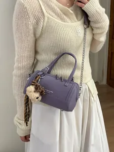 Purple cylindrical bag with silver chain strap and plush puppy charm on female model