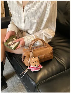 Détail du sac Boston marron avec boucle métallique et pendentif chien teddy en pull rayé