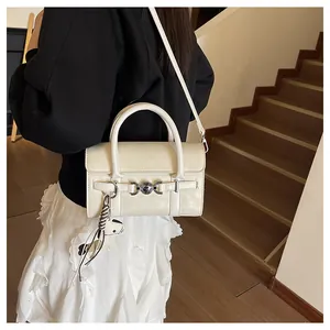 Détail du sac baguette crème avec boucle argentée et breloque dalmatien sur la bandoulière