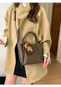 Détail d'un sac seau en cuir marron foncé avec cordon tressé et charm ours en peluche