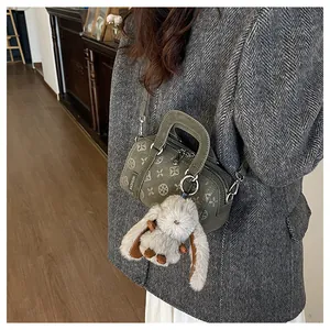 Detailed macro of olive green Boston bag featuring geometric floral patterns and plush rabbit charm