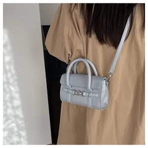 Détail du sac baguette bleu clair avec boucle argentée porté sur un trench beige