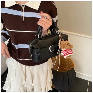 Détail d'un sac à main noir style motard avec boucle argentée et charm ours en peluche