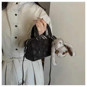 Macro detail of dark brown embossed Boston bag with skull patterns and bunny charm