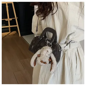 Detail of vintage brown embossed baguette bag with rabbit charm and fashion tag