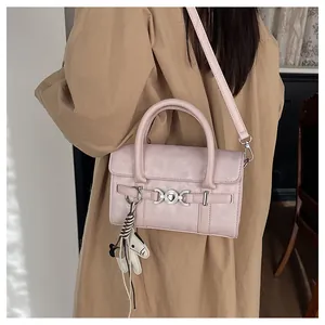 Détail du sac baguette rose avec boucle coeur et breloque chien sur un trench-coat chic