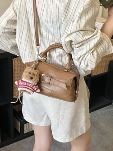 Sac baguette vintage marron avec breloque ours porté à l'épaule par un mannequin
