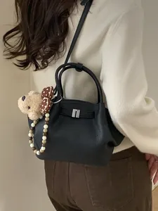 Elegant black lychee leather bucket bag with silver U-buckle and cute plush bear charm