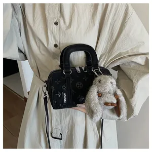 Detail of black embossed mini Boston bag with rabbit charm and Fashion label