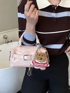 Sac baguette minimaliste rose avec pendentif ours présenté dans un décor intérieur moderne