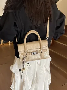 Sac baguette en similicuir beige avec boucle en métal et breloque cheval sur modèle
