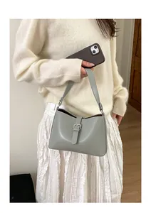 Sac à bandoulière vert sauge minimaliste avec boucle porté par un mannequin femme