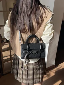 Sac baguette rétro noir avec boucle argentée et pendentif blanc porté par le mannequin