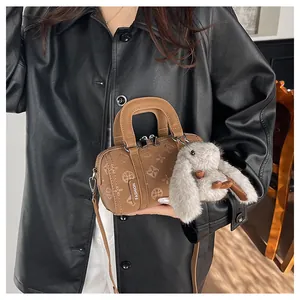 Macro detail of brown embossed baguette bag with fashion tag and plush rabbit charm