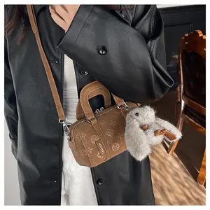 Detail of a brown leather cylinder bag with geometric embossing and a cute rabbit charm
