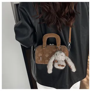 Detailed close-up of brown Boston bag with geometric pattern and bunny charm accessory
