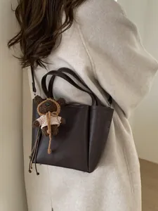 Sac seau rétro marron foncé avec charme d'ours en peluche porté par un mannequin